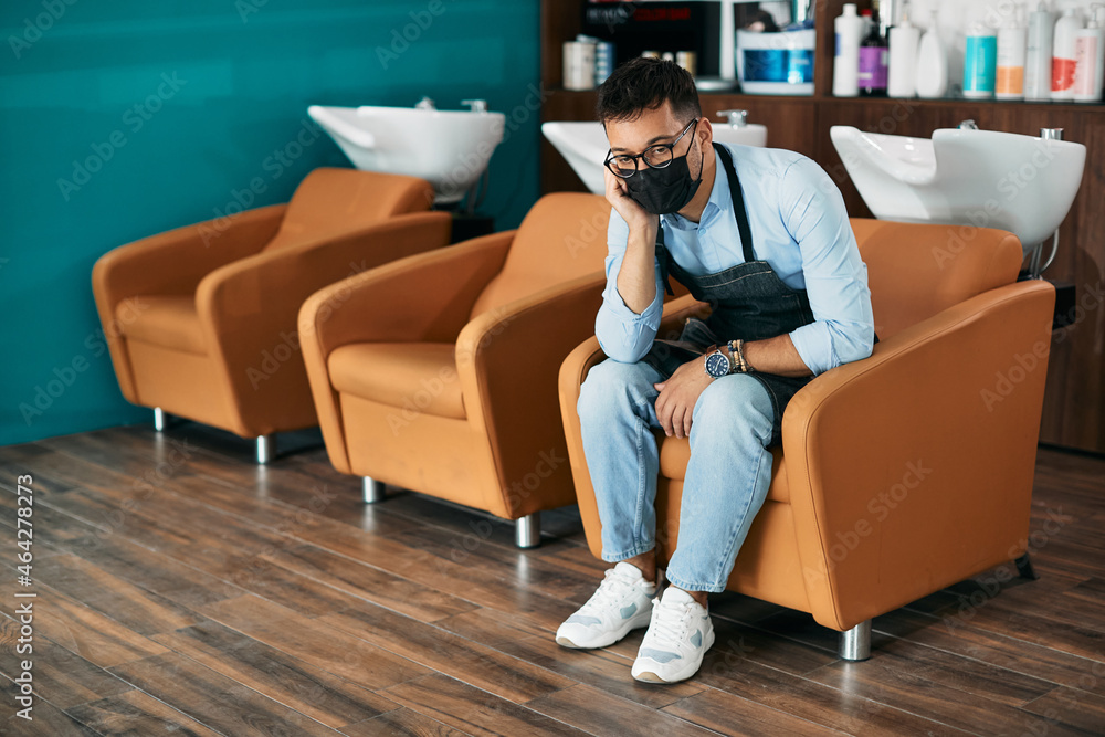 Obraz premium Pensive hairdresser feels worried about his business due to coronavirus pandemic.