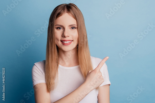 Photo of reliable cheerful lady indicate finger empty space toothy smile recommendation on blue color background