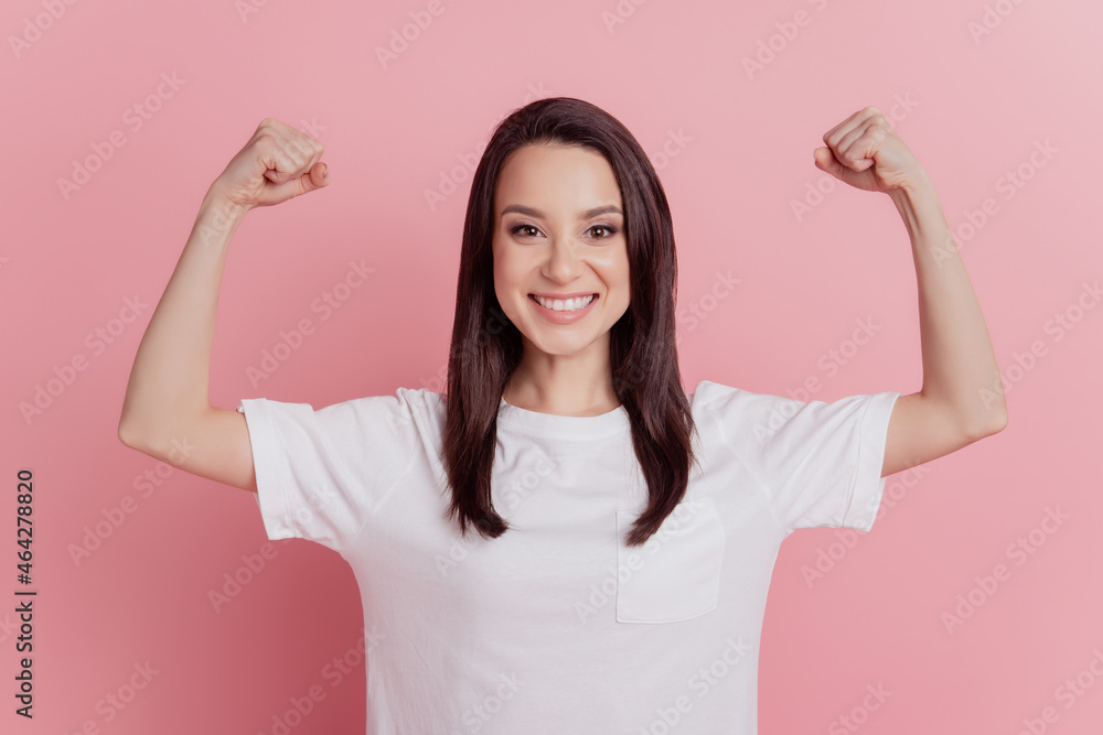 Photo of young cheerful girl show hands muscles biceps sporty body care isolated over pink color background Photo of young cheerful girl show hands muscles biceps sporty body care isolated over pink color background