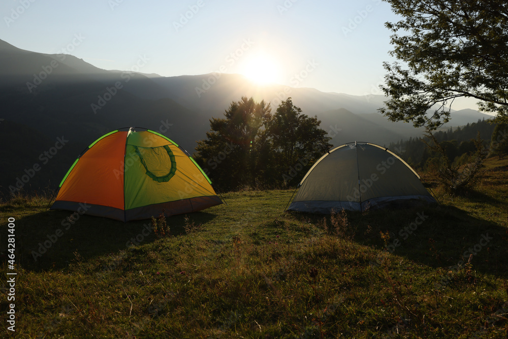 Two color camping tents on hill in mountains