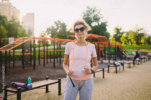 Regular exercise is big part of healthy lifestyle. Happy mature woman relaxing after jumping training. Concept active lifestyle and healthcare in mature age. Senior lady standing with skipping rope photo