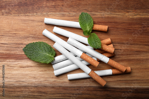 Cuadro en lienzo Menthol cigarettes and mint leaves on wooden table, flat lay