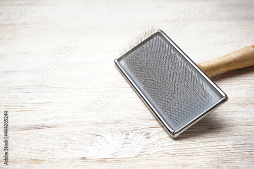 Brush for dogs on a wooden background, space for text. Brush for grooming wool. Close-up.