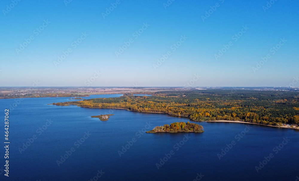 Obraz premium Island in the sea with a beautiful autumn forest. Aerial top view