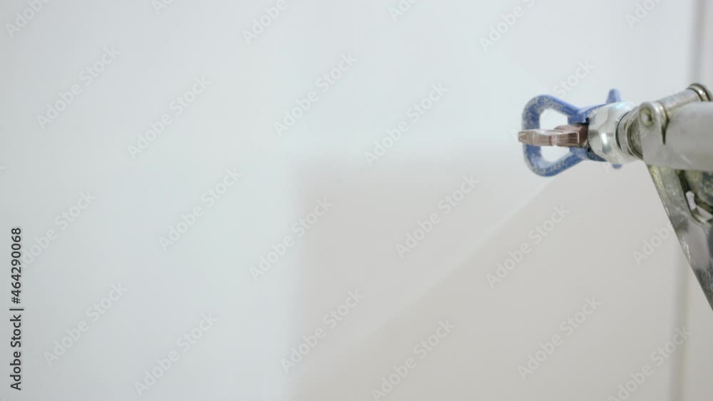 Painting the wall white with a spray gun during repairs Painting the wall white with a spray gun during repairs