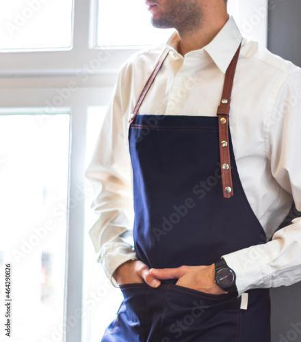 man wearing navy blue strappy barista apron