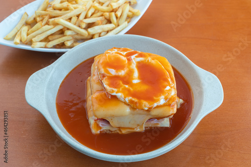 Francesinha is a Portuguese sandwich, made with bread, ham, linguica, sausage, steak, and covered with, cheese and beer sauce. Close up photo