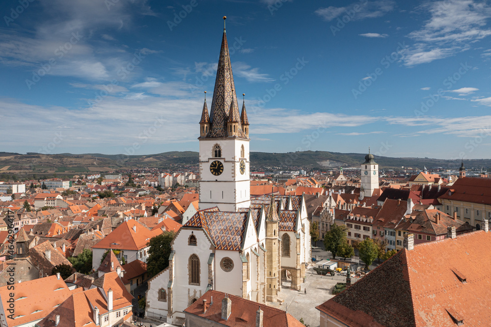 Landmarks of Romania. Aerial view of the old center of Sibiu city at the bottom of Fagaras Mountains during a beautiful sunny day with blue sky. Evangelical Cathedral after restoration.