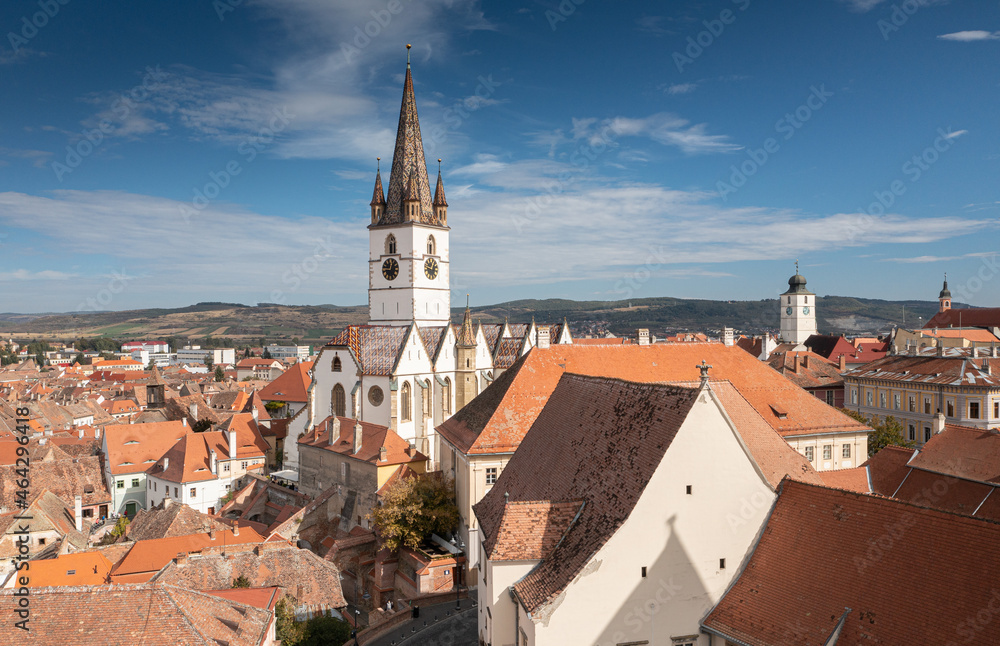Landmarks of Romania. Aerial view of the old center of Sibiu city at the bottom of Fagaras Mountains during a beautiful sunny day with blue sky. Evangelical Cathedral after restoration.