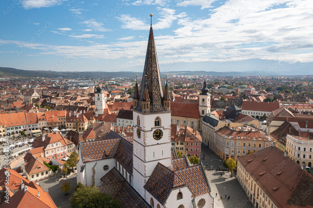 Landmarks of Romania. Aerial view of the old center of Sibiu city at the bottom of Fagaras Mountains during a beautiful sunny day with blue sky. Evangelical Cathedral after restoration.