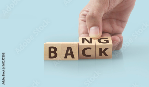 The hand puts wooden cube with the letter from the word back and bang. wooden cubes standing in hand
