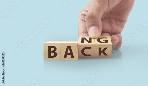The hand puts  wooden cube with the letter  from the word back and bang. wooden cubes standing  in hand