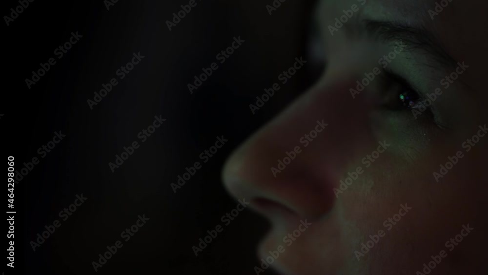 Daughter looks at a large dressed-up glowing New Year tree. The girl's eyes close up on the black background. Talking about something. Bokeh as background. Concept of Christmas, new year holidays. Daughter looks at a large dressed-up glowing New Year tree. The girl's eyes close up on the black background. Talking about something. Bokeh as background. Concept of Christmas, new year holidays.