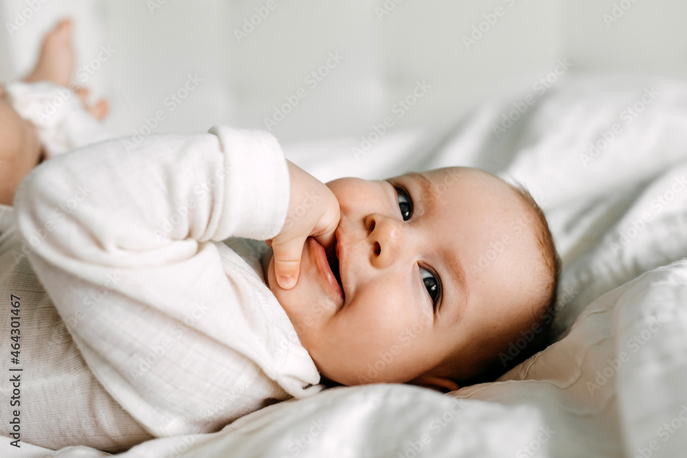 Baby lying in bed, smiling, sucking fingers. Baby lying in bed, smiling, sucking fingers.