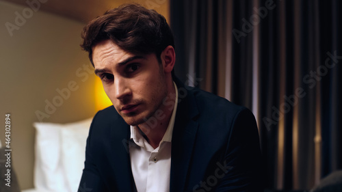 worried businessman looking at camera in hotel room.