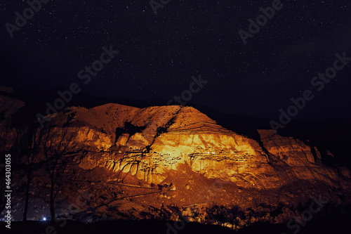 Starry night in famous tourist destination in Georgia-Illuminated Vardzia cave city. Romantic evening in wilderness under the stars.