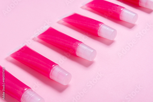 Lot of homemade lip glosses on pink background