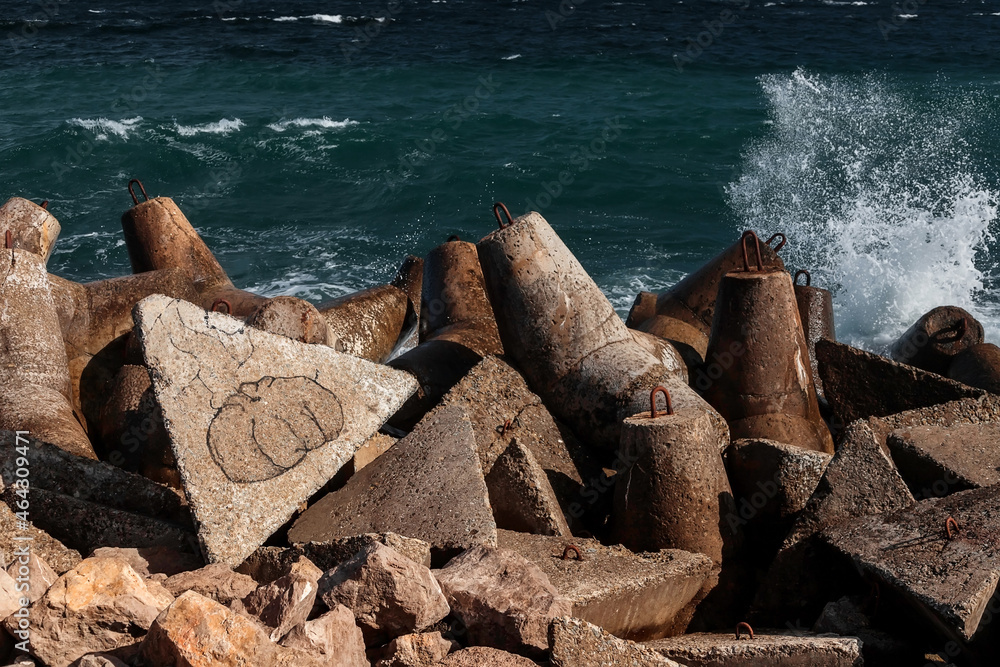 Strengthening the shore from erosion with concrete tetrapods. The seashore with concrete blocks. The element of water. Waves break on concrete. Strengthening the shore from erosion with concrete tetrapods. The seashore with concrete blocks. The element of water. Waves break on concrete.