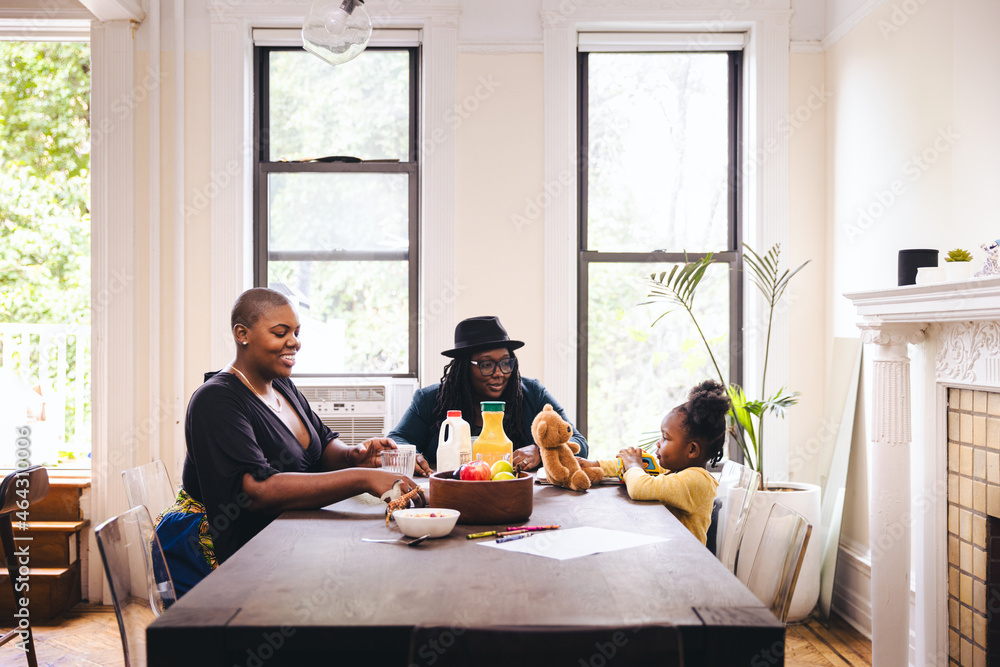 Lesbian parents with daughter at table in dining room Lesbian parents with daughter at table in dining room