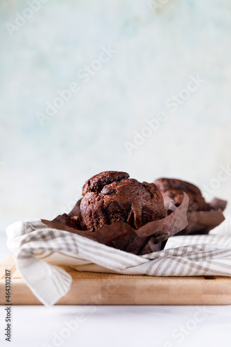Chocolate muffin with paper wrap and an ounce of chocolate on a wooden base