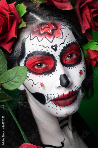joven mujer calavera pintada en el rostro y flores dia de los muertos mexico katrina catrina sobre fondo verde Closeup close up photo