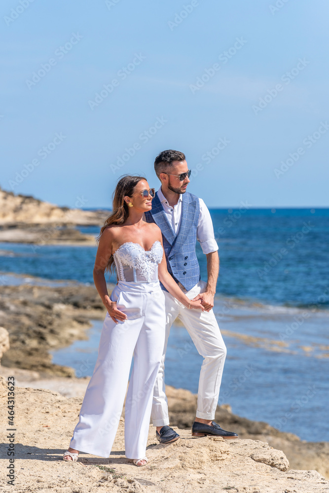 Newlyweds holding hands on shore near ocean Newlyweds holding hands on shore near ocean