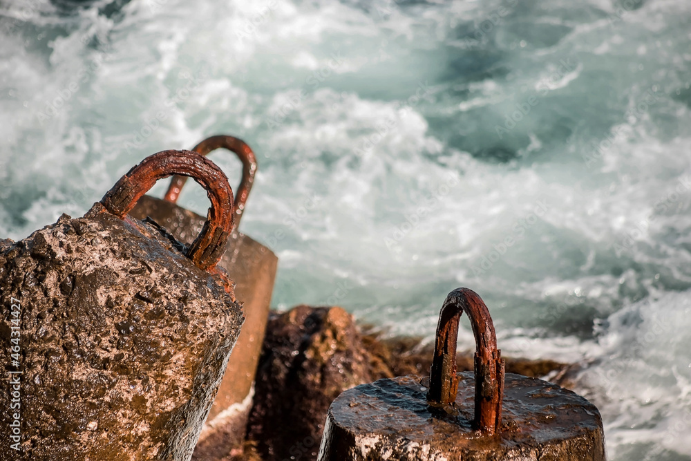Fototapeta premium Strengthening the shore from erosion with concrete tetrapods. The seashore with concrete blocks. The element of water. Waves break on concrete.