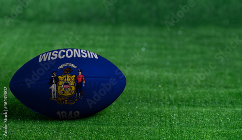 American football ball with Wisconsin flag on green grass background, close up