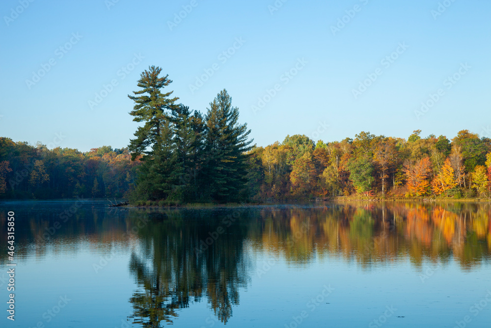 Beautiful calm lake with trees in autumn color and a small island in northern Minnesota at dawn