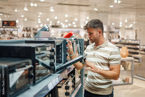 Man looking inside microwave oven in shop