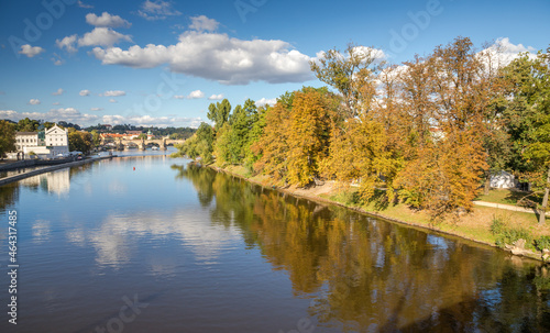 autumn park on the island near the Charles Bridge is reflected on the river surface