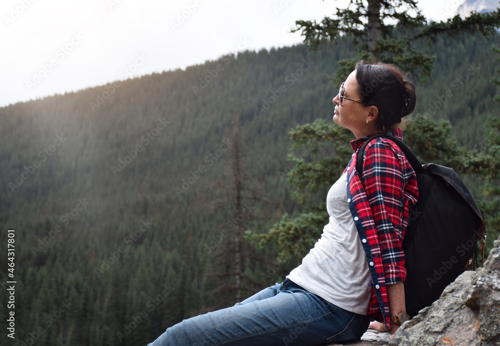Portrait of woman hiker sitting on rocks resting after a hike enjoying a view