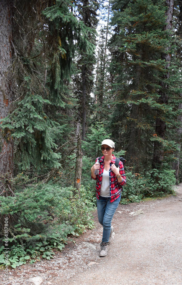 Woman with hiking backpack walking on forest trail