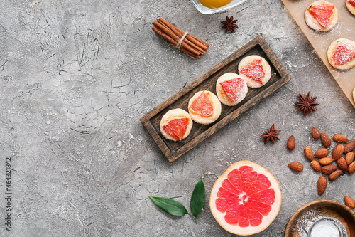 Composition with board of tasty grapefruit cookies and ingredients on grunge background