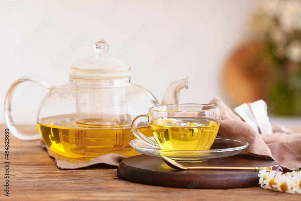 Teapot and cup of fresh chamomile tea on wooden table Teapot and cup of fresh chamomile tea on wooden table