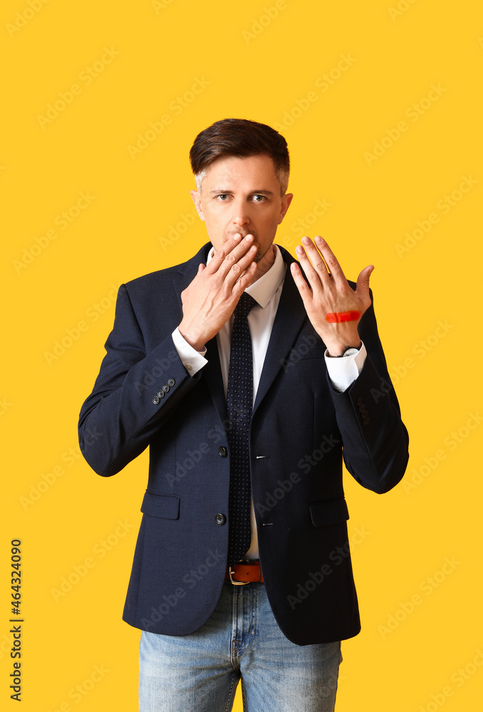 Shocked businessman with medical patch on his wrist against color background Shocked businessman with medical patch on his wrist against color background