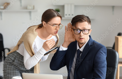 Male and female colleagues gossiping in office photo