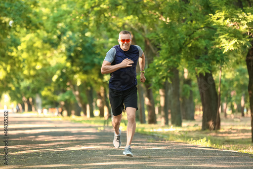 Sporty mature man with eyeglasses running in park