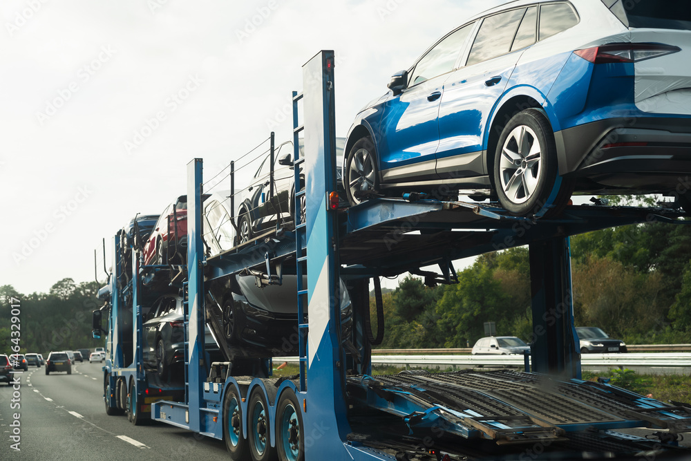 Naklejka premium A car transporter loaded with vehicles moving at speed on a motorway.