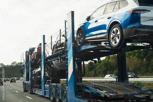 A car transporter loaded with vehicles moving at speed on a motorway.