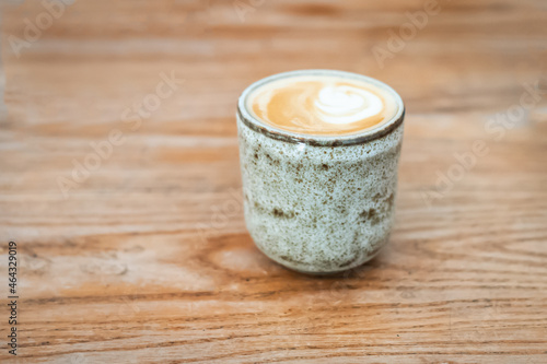 Milky coffee in an earthenware mug with no handles on wooden table