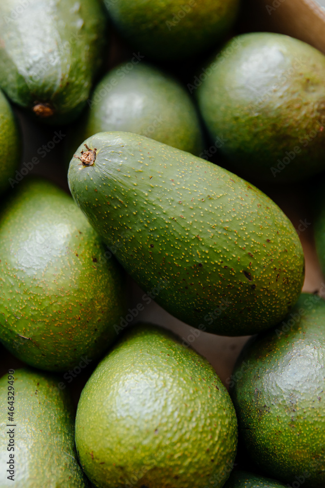 Lots of green fresh avocados in a box on the counter in the store, Lots of green fresh avocados in a box on the counter in the store,