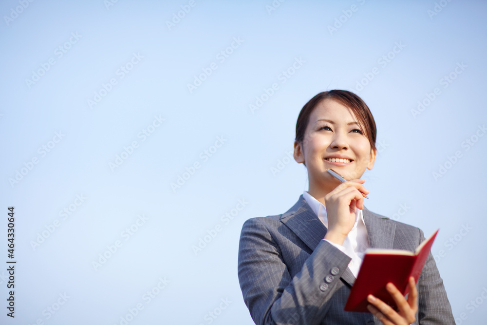 手帳を開き考え事をするビジネスウーマン