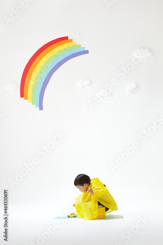 虹の下で黄色のカッパを着た遊ぶ子ども photo