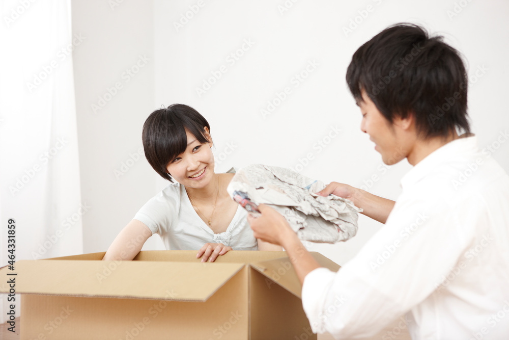 ダンボールに荷物を詰める笑顔の女性と男性のカップル ダンボールに荷物を詰める笑顔の女性と男性のカップル