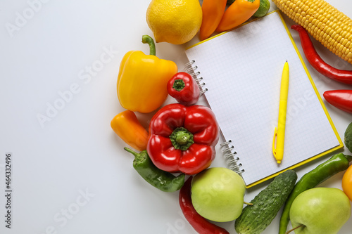 Blank notebook, pen, vegetables and fruits on white background. Vegan Day, closeup
