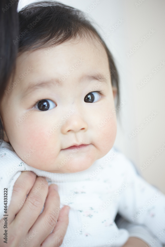お母さんに抱かれてこちらを見る可愛い赤ちゃんの女の子 お母さんに抱かれてこちらを見る可愛い赤ちゃんの女の子