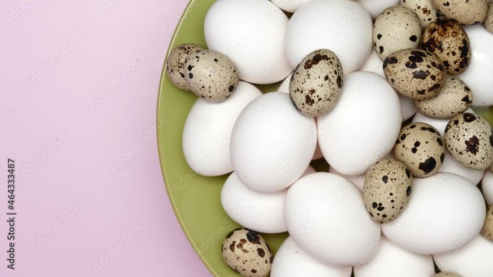 Rotating White Chicken Eggs With Quail Eggs On A Green Plate On A Pink Background On Right Side. Top View. Close Up. Rotating White Chicken Eggs With Quail Eggs On A Green Plate On A Pink Background On Right Side. Top View. Close Up.