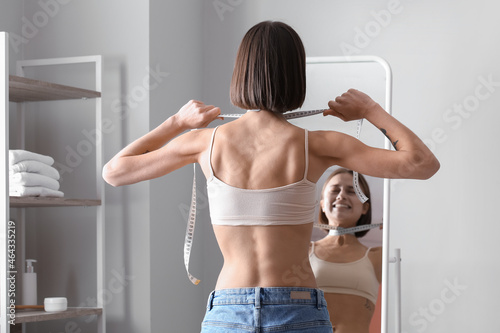 Foto Young skinny woman in front of mirror at home. Anorexia concept