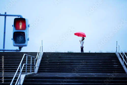 川の土手の階段前で傘を持ってたたずむ女性 ,日本,大阪府,大阪市,淀川区,新北野2丁目